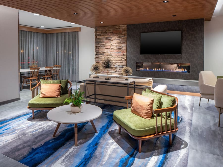 Un salon moderne avec un mur d’accent en pierre, un téléviseur à écran plat, une cheminée et un tapis à motifs bleus.