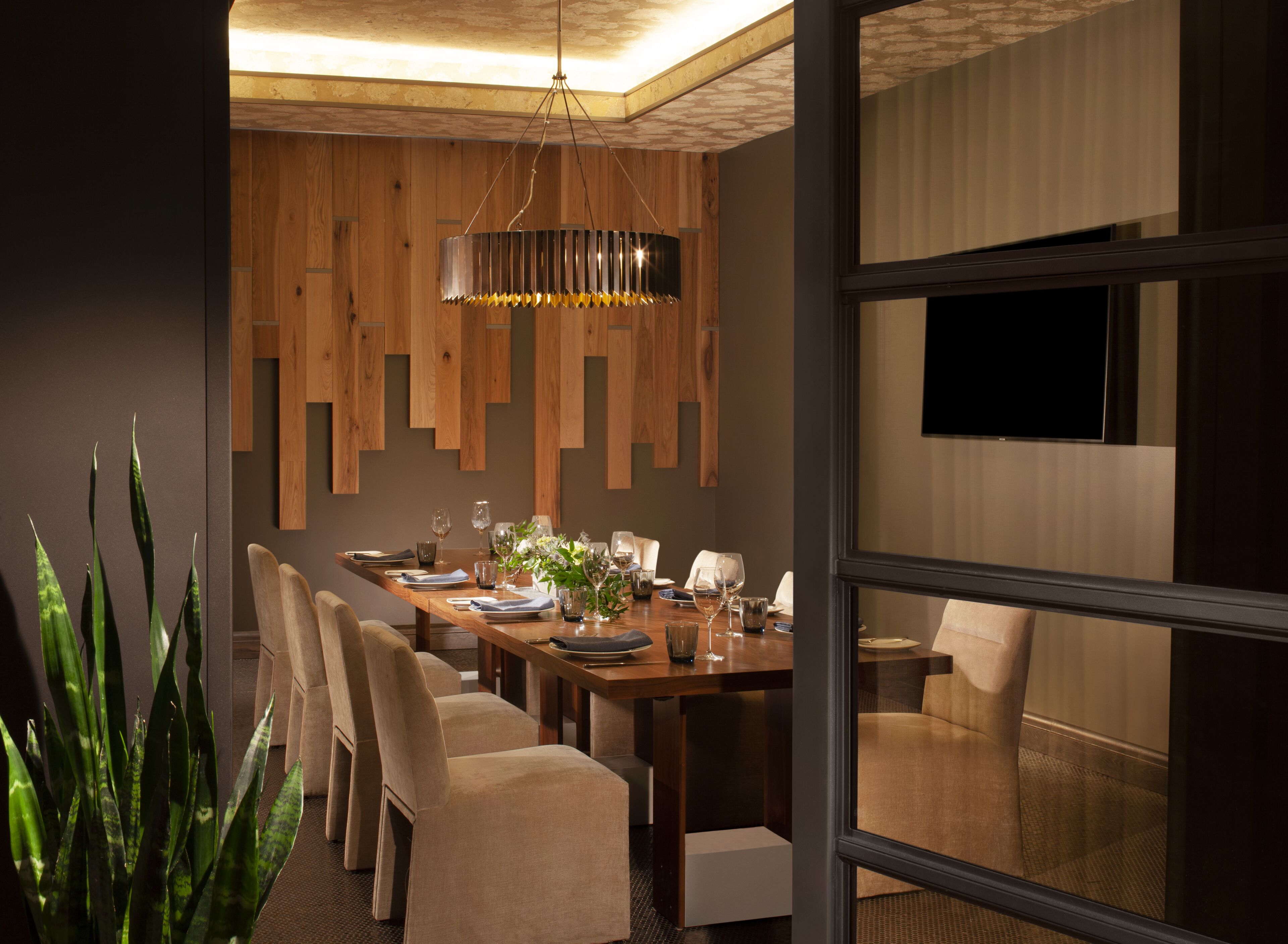 Une salle à manger moderne avec une table en bois, des chaises et un luminaire suspendu.