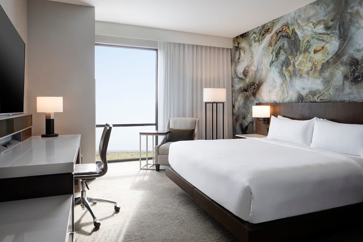 Une chambre d’hôtel avec un grand lit, un bureau, une chaise, une télévision et une vue sur l’extérieur.