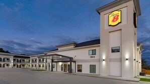 A Super 8 hotel with a modern design, featuring a prominent logo on the facade, multiple balconies, and a covered entrance area. - Super 8 by Wyndham Houston NW Beltway 8/West Rd (Houston)