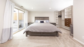 A bedroom with a bed, a nightstand, a wardrobe, and a sliding glass door to the outside.