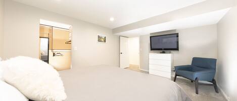 Un dormitorio con cama, una silla, televisor y armario.