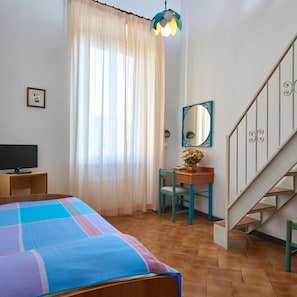A bedroom with a bed, a desk, a chair, a television, a mirror, and a staircase. - Hotel Garibaldi (Finale Ligure)