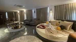 A modern hotel room with a round bed, a sofa, a dining area, and a view of the city. - Le Luxe suites hotel & SPA (Bursa)