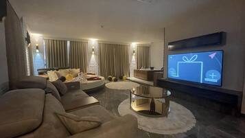 A modern living room with a large flat-screen TV mounted on the wall, a comfortable sofa, a coffee table, and a decorative rug.