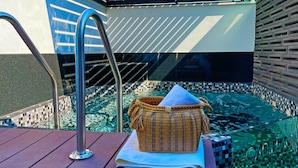 A hot tub with a woven basket and a towel, a metal ladder, and a tiled wall. - Cadillac Hotel Boutique (Mexico City)