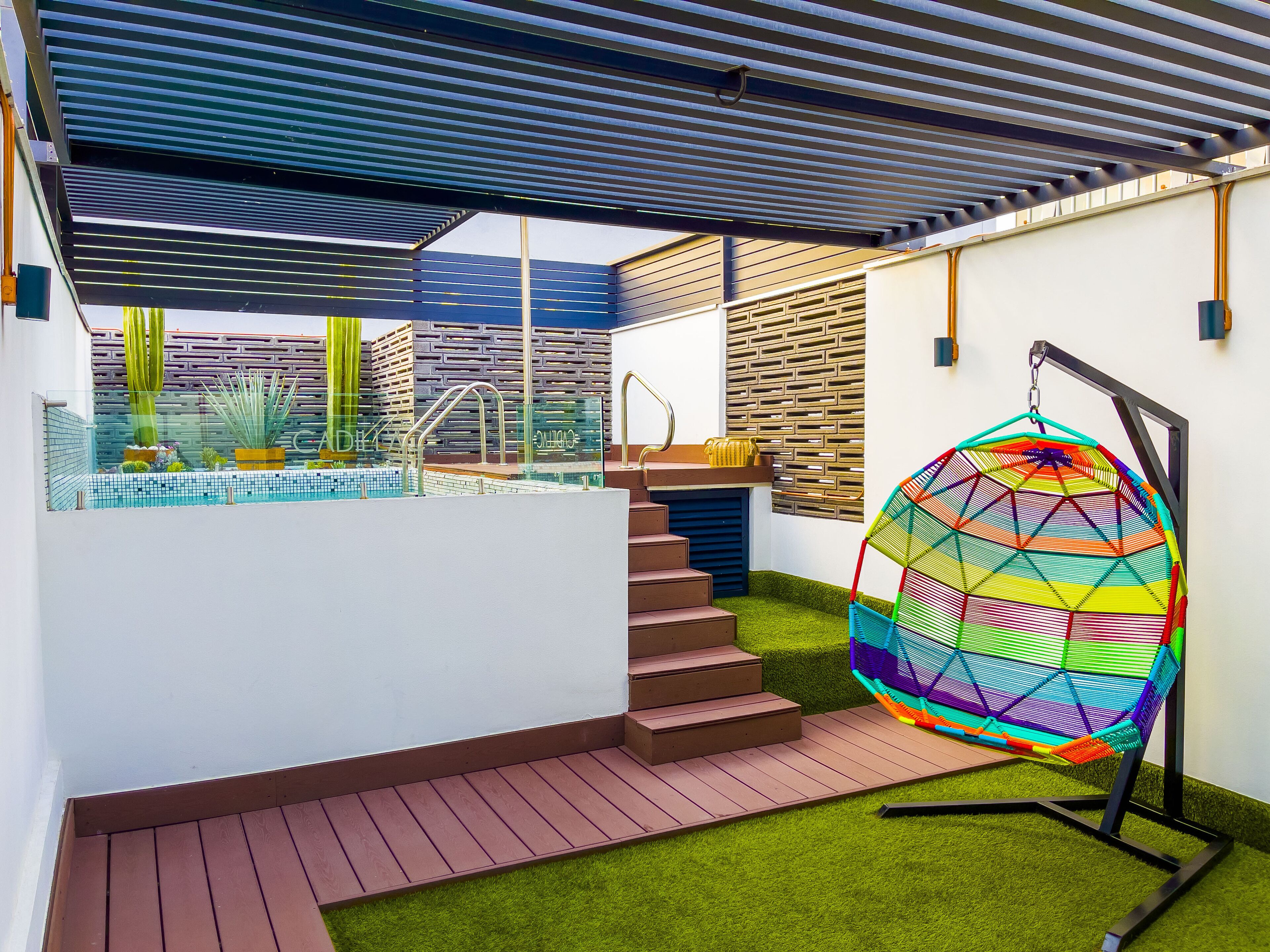 A modern outdoor area with a pool, a hanging chair, and a staircase leading to a deck.