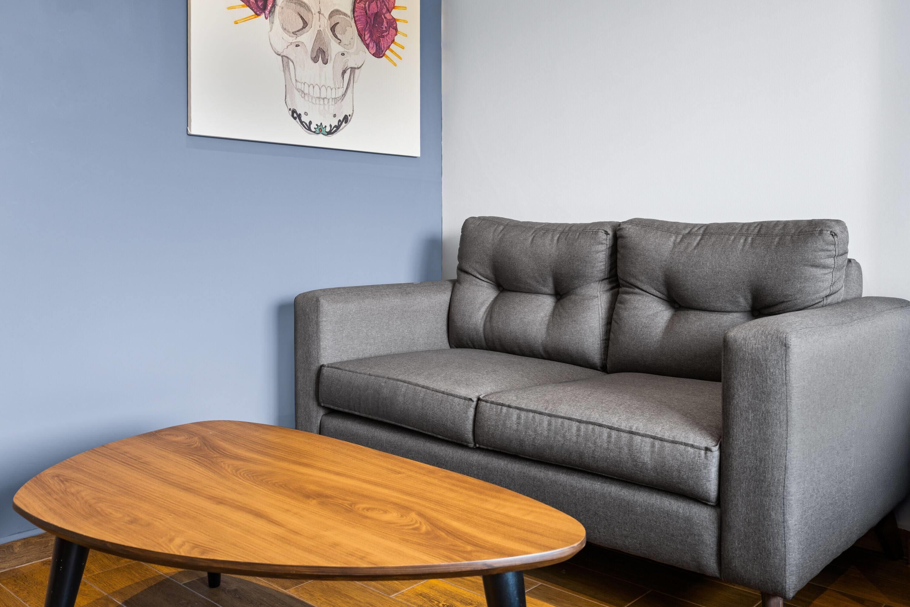A grey sofa with a wooden coffee table in a room with blue walls.