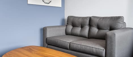 A grey sofa with a wooden coffee table in a room with blue walls.