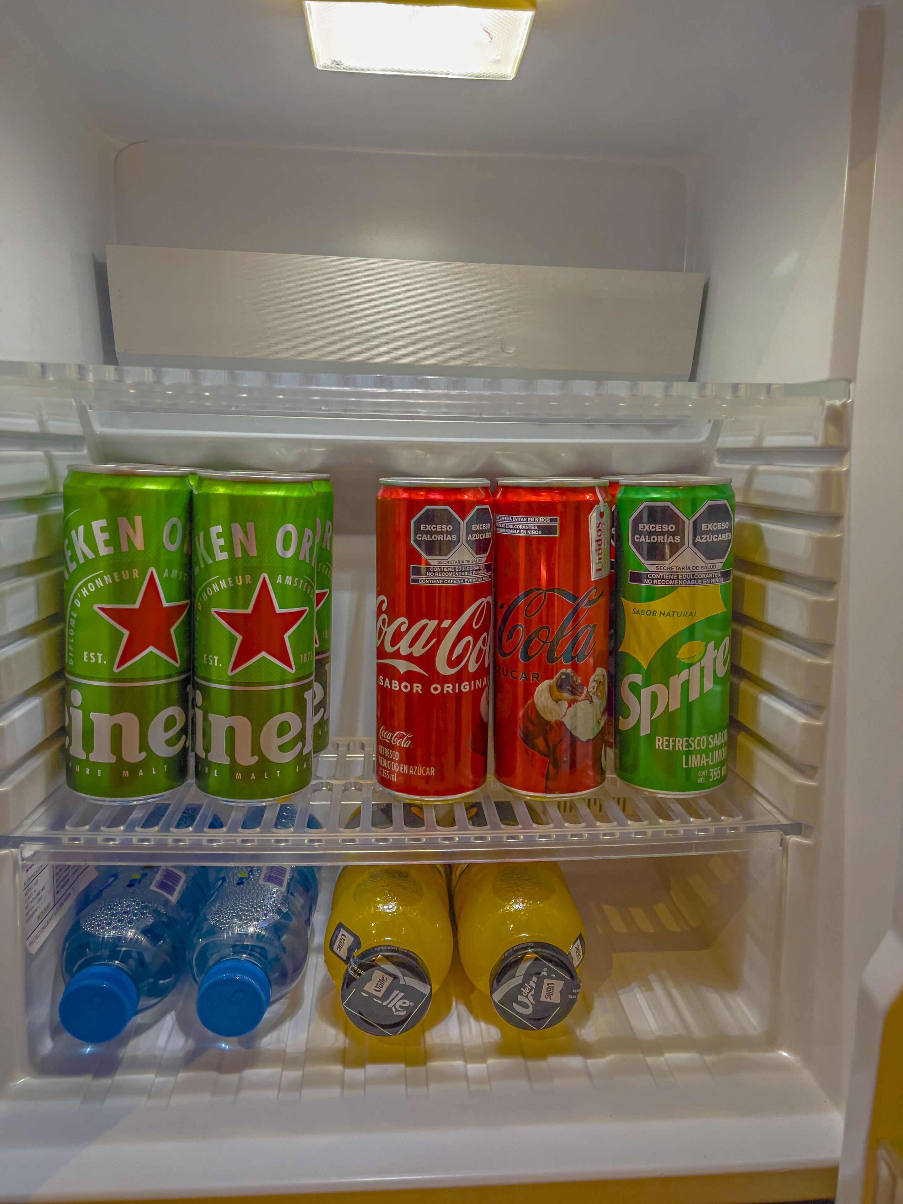 A refrigerator shelf with various beverages including Heineken, Coca-Cola, Sprite, and bottled water.