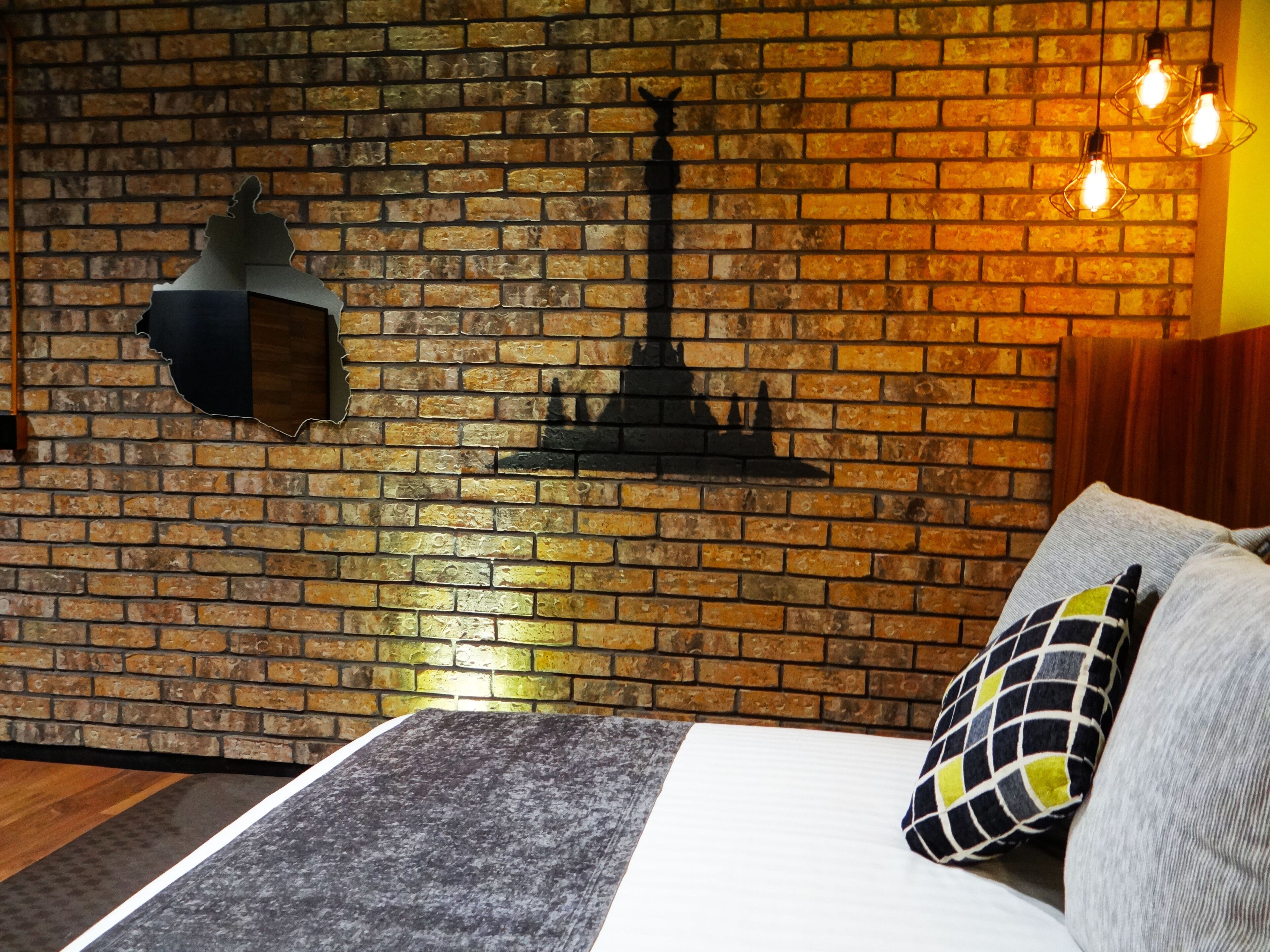 A room with a brick wall, a fireplace, and a bed with a patterned pillow.