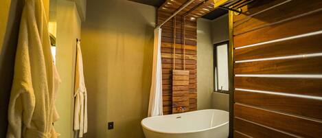Un baño moderno con una bañera independiente, paneles de madera y un cartel que indica la ubicación como el Hotel Cadillac.