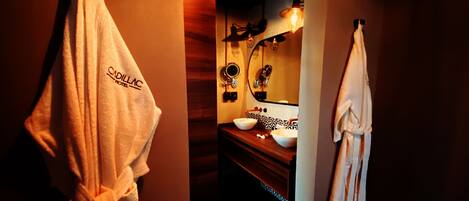 A hotel bathroom with a wooden vanity, two sinks, a mirror, and towels hanging on the wall.