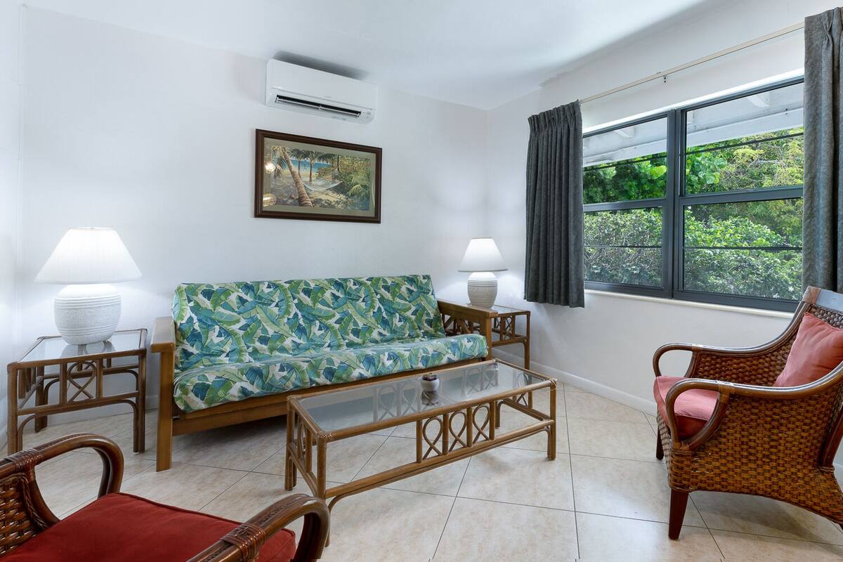 A living room with a sofa, two side tables, a coffee table, and wicker chairs.