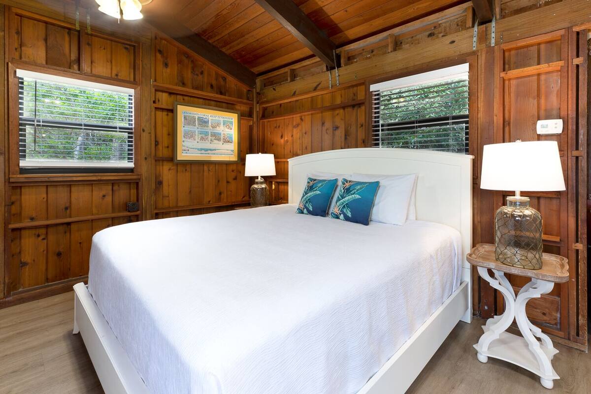 A wooden room with a large bed, two bedside lamps, and a framed informational poster on the wall.