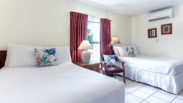Habitación de hotel con dos camas, una silla, una lámpara y un ventanal con cortinas.