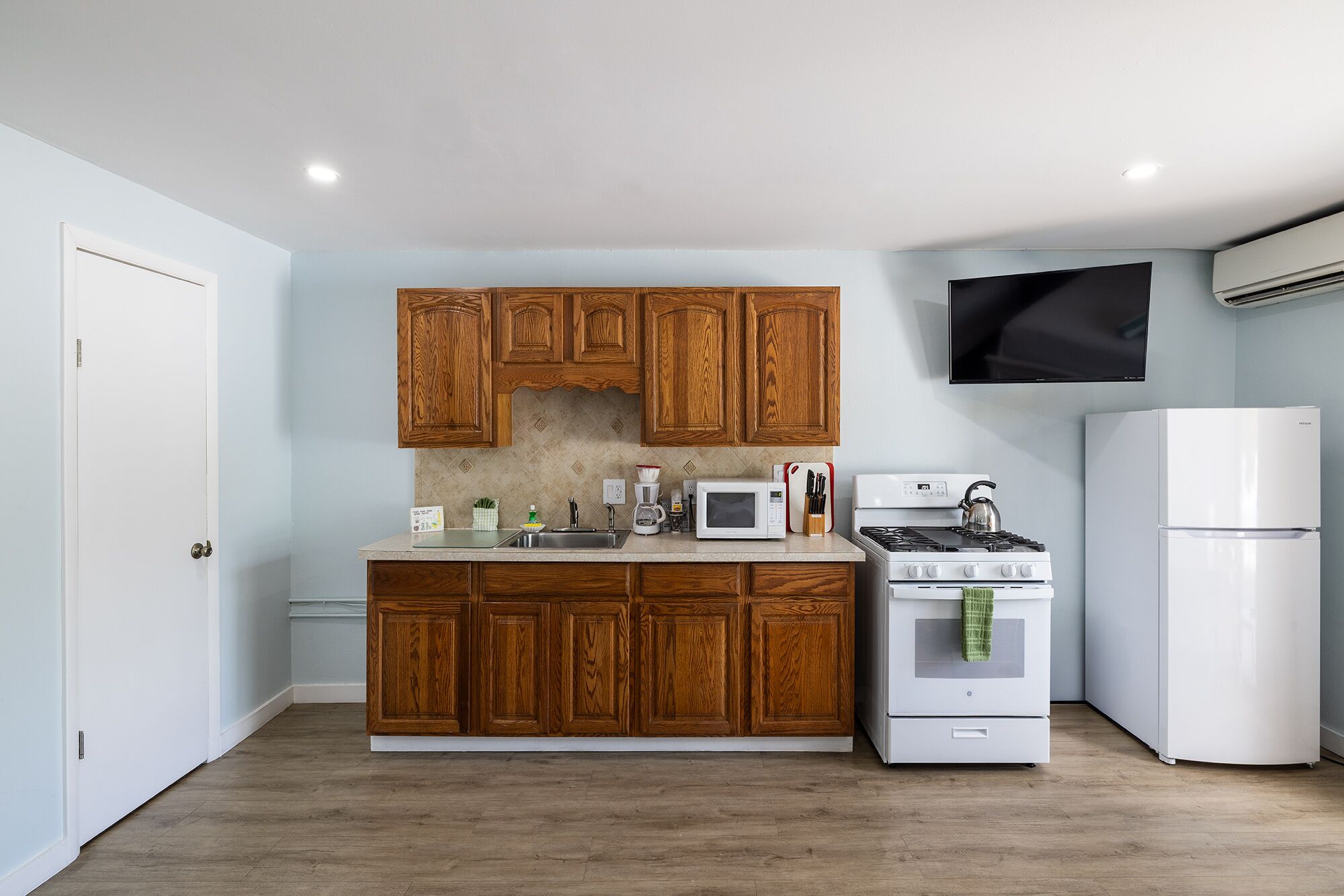 Une cuisine avec des meubles de rangement en bois, un four à micro-ondes, une cuisinière et un réfrigérateur.