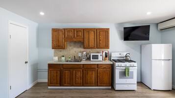 Une cuisine avec des meubles de rangement en bois, un four à micro-ondes, une cuisinière et un réfrigérateur.