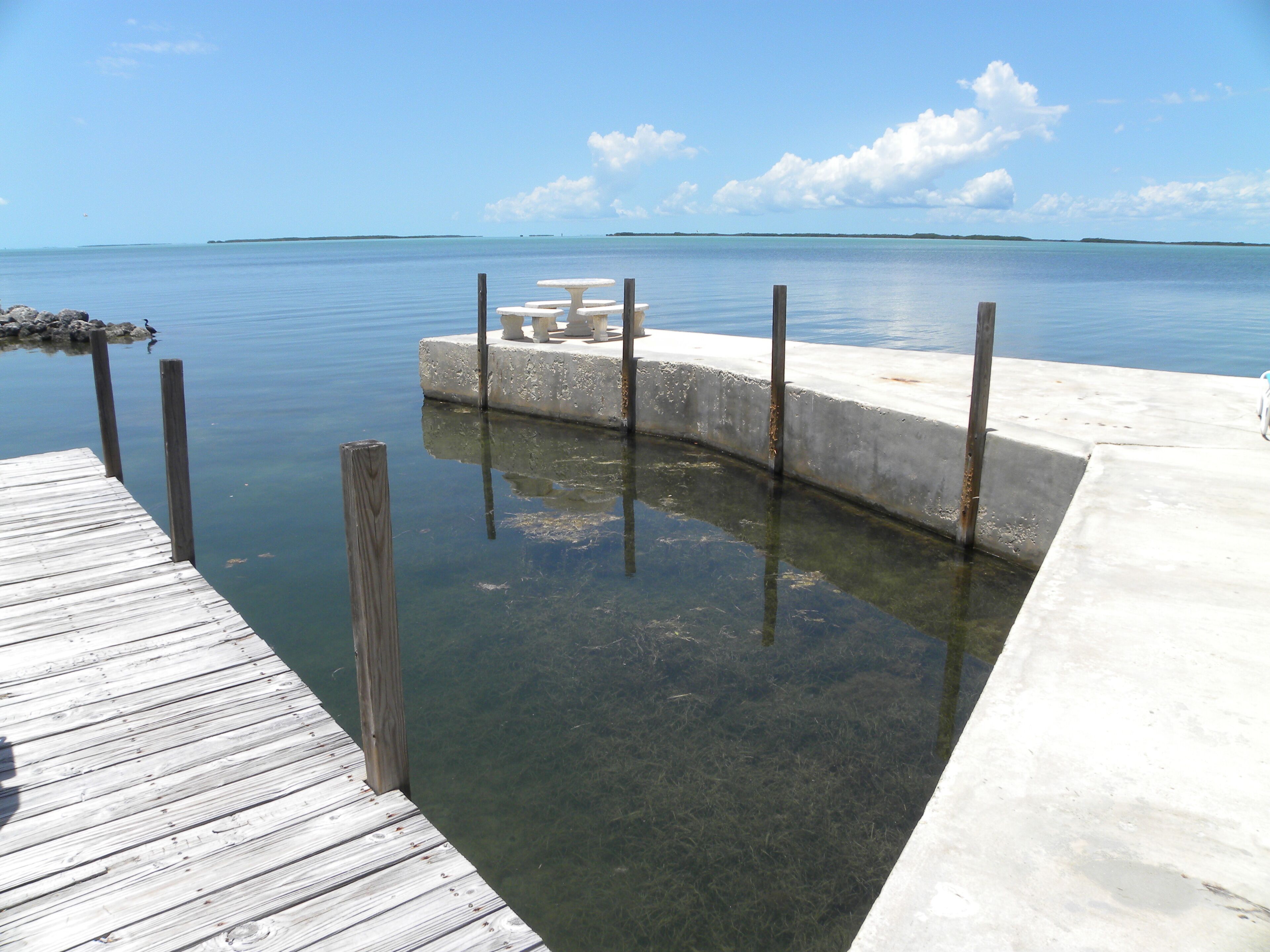 A concrete dock with a small concrete platform and a wooden pier.