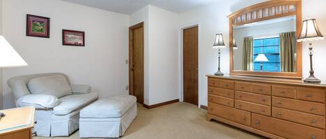 A bedroom with a bed, a dresser, a mirror, and two framed pictures on the wall.