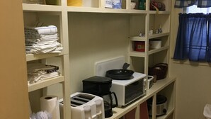 Une cuisine avec des meubles blancs, un four à micro-ondes, un grille-pain et divers ustensiles de cuisine.