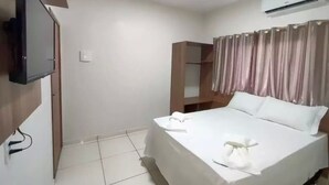 A hotel room with a bed, a television mounted on the wall, a wardrobe, and an air conditioning unit. - Hotel Araguaia (Canaa dos Carajas)