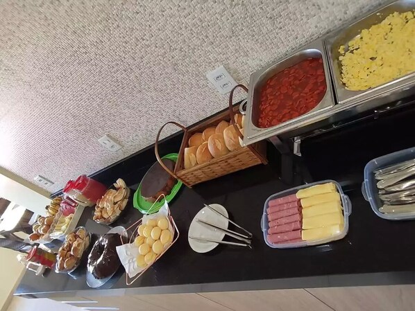 Un bufé con diversas opciones de comida, incluyendo pan, pasteles y carnes.