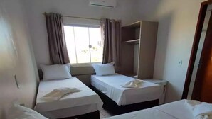 A hotel room with two single beds, a window with curtains, an air conditioning unit, and a wardrobe. - Hotel Araguaia (Canaa dos Carajas)