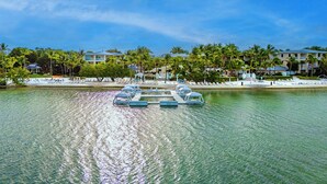 A resort with a water body, lounge chairs, and a pool area.