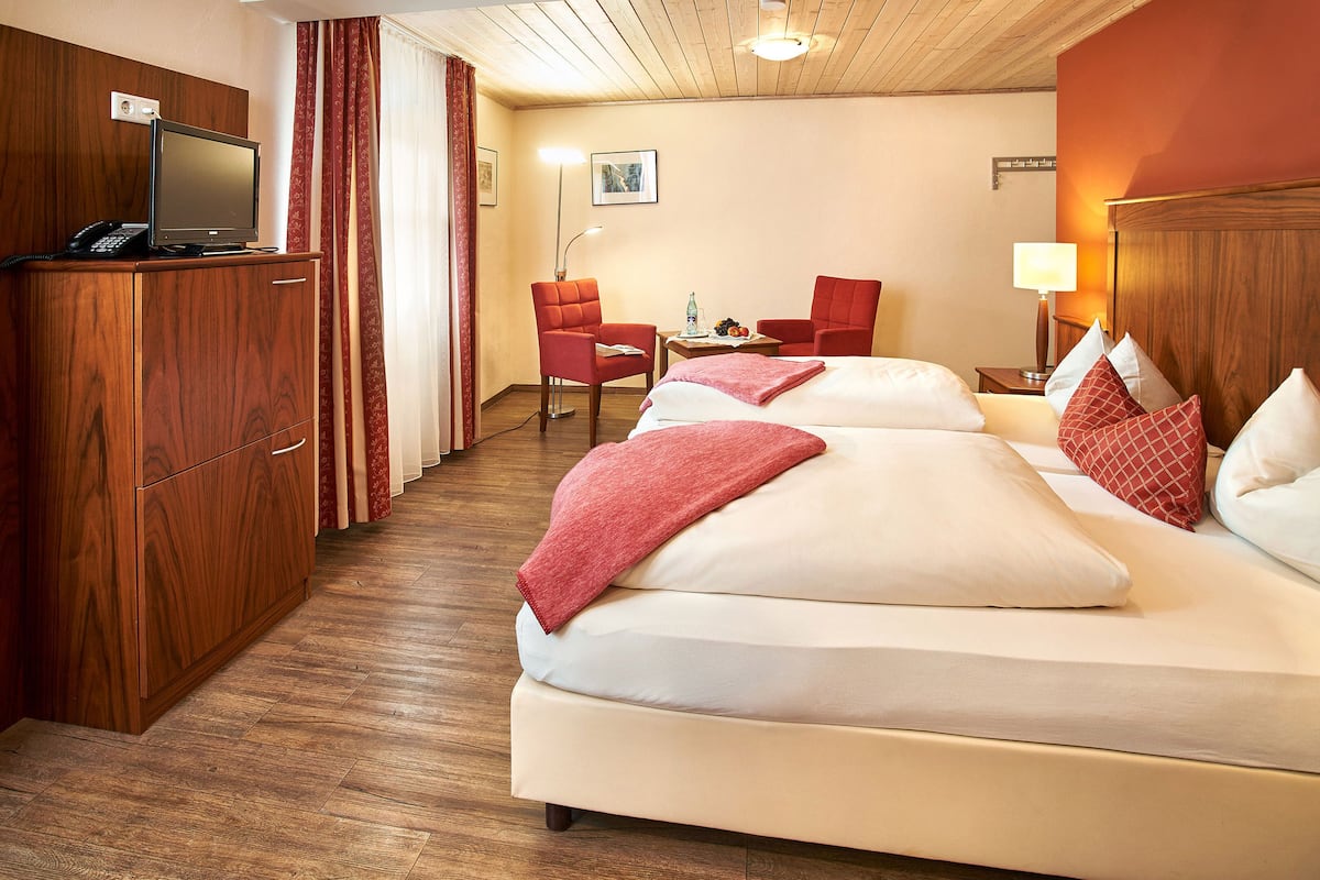 Ein Hotelzimmer mit zwei Betten, einem Schreibtisch, einem Stuhl, einem Fernseher und einer Lampe.