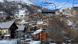 A ski resort with wooden chalets, a ski lift, and a sign for 'Moulin Benjamin'.