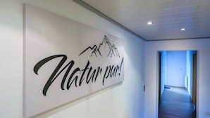 Un pasillo con un cartel que dice 'Natur pur!' y vista de un suelo de madera y una puerta al final.