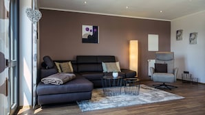 Una sala moderna con un sofá modular, una mesa de centro redonda y un sillón gris.