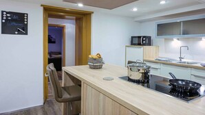 Una cocina moderna con encimera de madera, microondas, estufa y un pequeño rincón de estar.