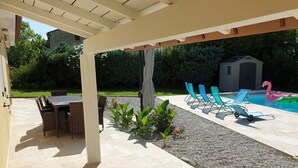 A covered patio with a pool, outdoor furniture, and a small shed in the background. - The Provençal villa. (Sarrians)