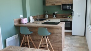 A modern kitchen with a wooden island, bar stools, and a dining table with a woven placemat. - The Provençal villa. (Sarrians)