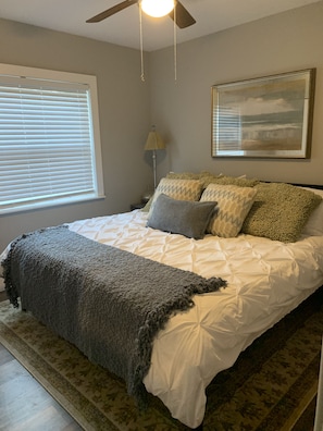 A bedroom with a bed, a ceiling fan, a lamp, and a framed picture on the wall. - Mid Century Gem Near Theme Parks (Ocoee)