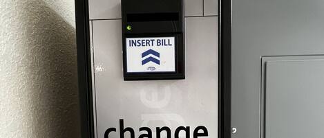Een verdeeldoos met een digitaal scherm en een keypad om biljetten in te stoppen, met de tekst 'INSERT BILL'.