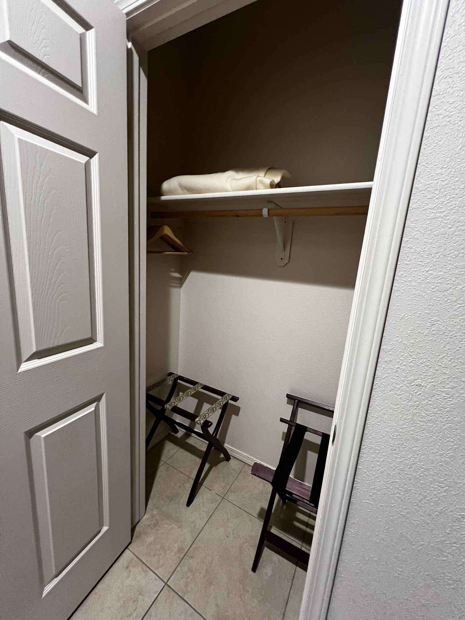 A closet with a hanging rod, a shelf, and a small table.
