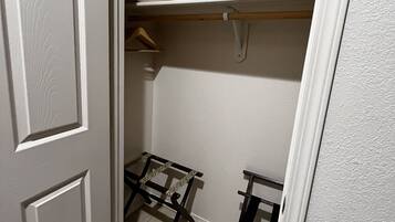 A closet with a hanging rod, a shelf, and a small table.