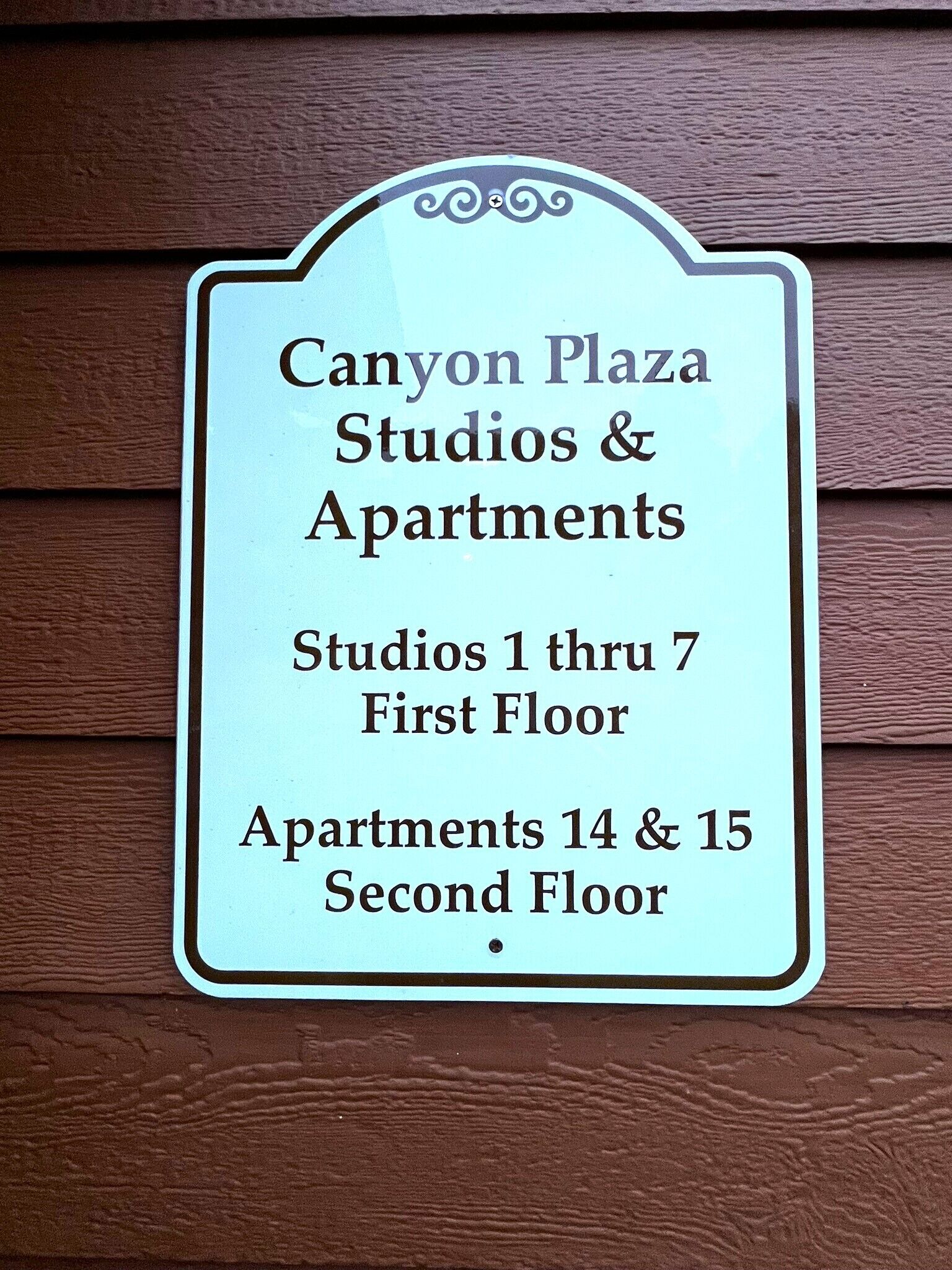 Une enseigne indiquant l’emplacement de Canyon Plaza Studios & Apartments, avec les studios numérotés de 1 à 7 au premier étage et les appartements numérotés 14 et 15 au deuxième étage.