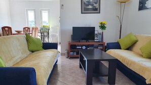 Uma sala de estar com dois sofás, uma mesa de centro, uma televisão e uma estante de livros.