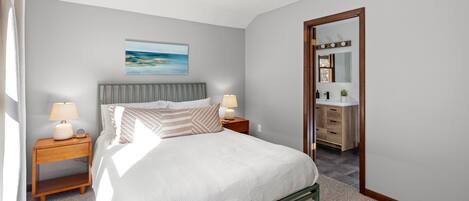 A bedroom with a bed, nightstands, a ceiling fan, a painting, and a bathroom visible through an open door.