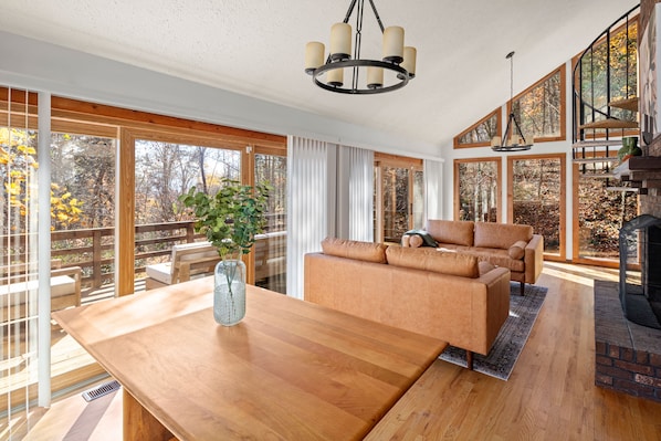 A spacious living room with a wooden dining table, a brown sofa, and a fireplace.