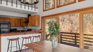 Una cucina moderna con mobili in legno, un frigorifero in acciaio inossidabile e un'ampia finestra vista bosco.
