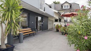 A modern building with a bench and potted plants in the courtyard. - Pension Jederzeit (Wallersdorf)