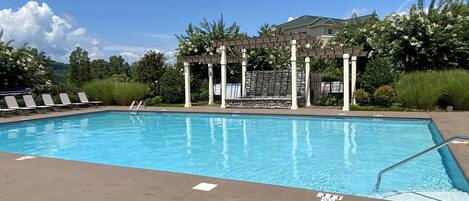 A swimming pool with a pergola, lounge chairs, and a lifeguard sign.