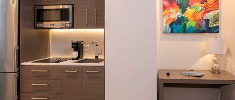 Una cocina moderna con microondas, cafetera y un cuadro en la pared.