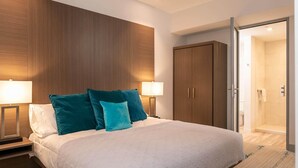 A modern hotel room with a large bed, two bedside lamps, a wardrobe, and a shower area. - Suite 11 with Large Bathroom (Cruz Bay)