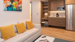 A modern living room with a sofa, a coffee table, and a kitchen area with a refrigerator, microwave, and cabinets. - Suite 11 with Large Bathroom (Cruz Bay)